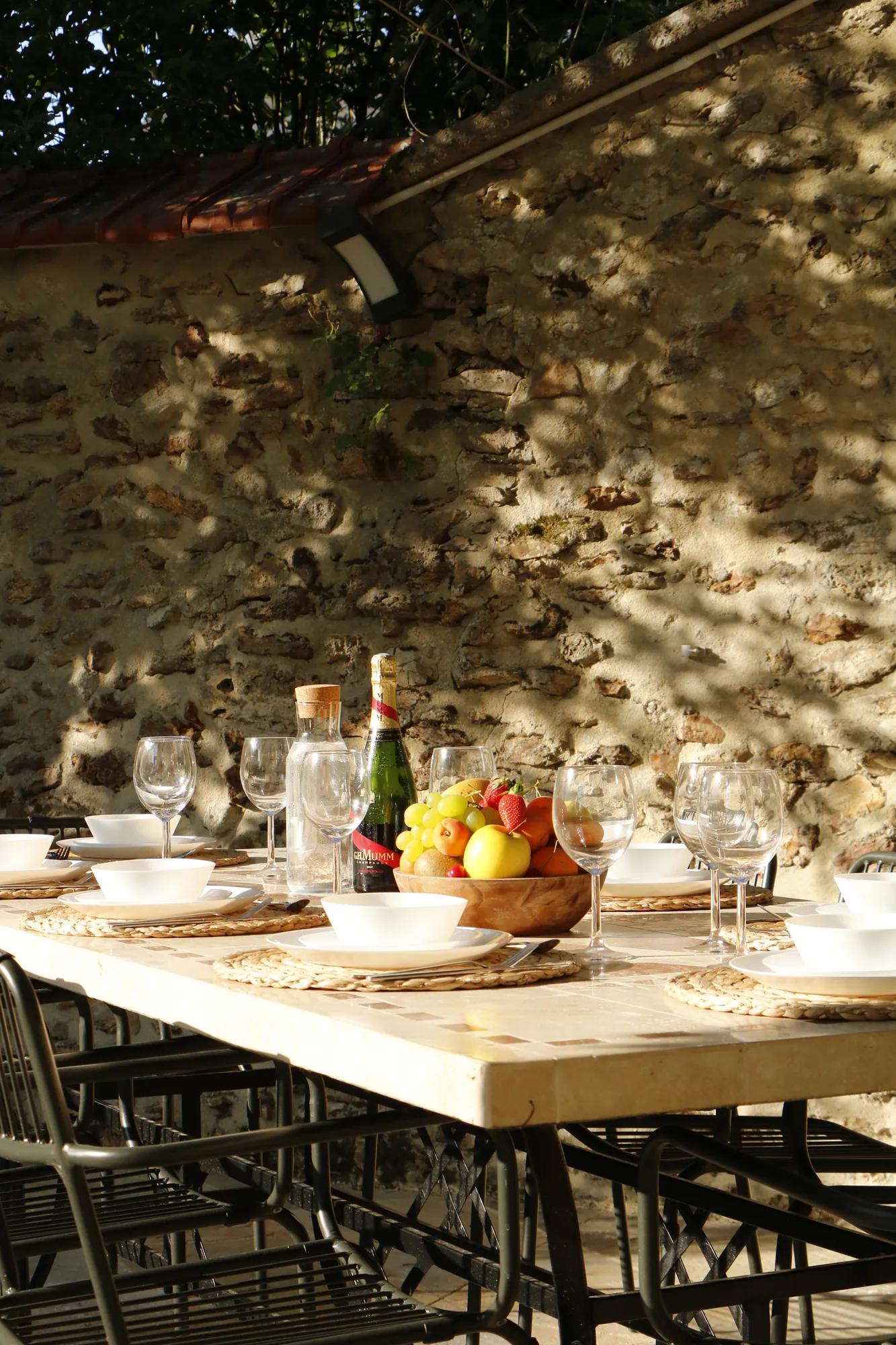 Table dressée dans la cour en pierre, fruits et champagne